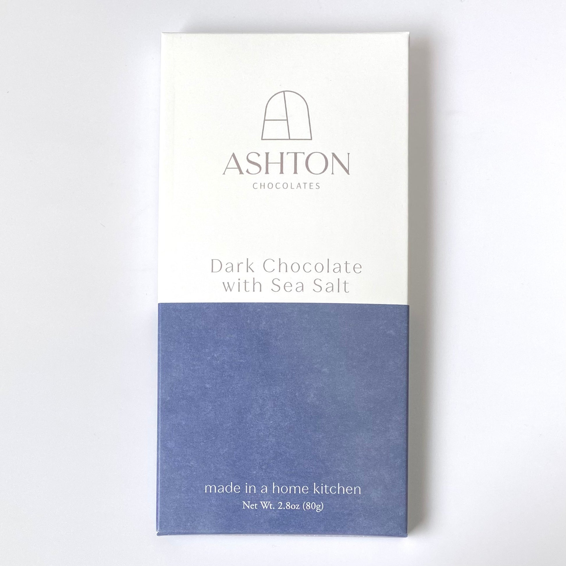 Dark Chocolate with Sea Salt bar in it's box on a white background. The box is half white half navy blue.