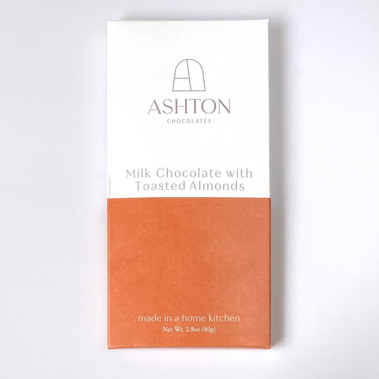 Milk Chocolate with Toasted Almonds bar box on a white back ground, the bo is white on top and orange on the bottom.